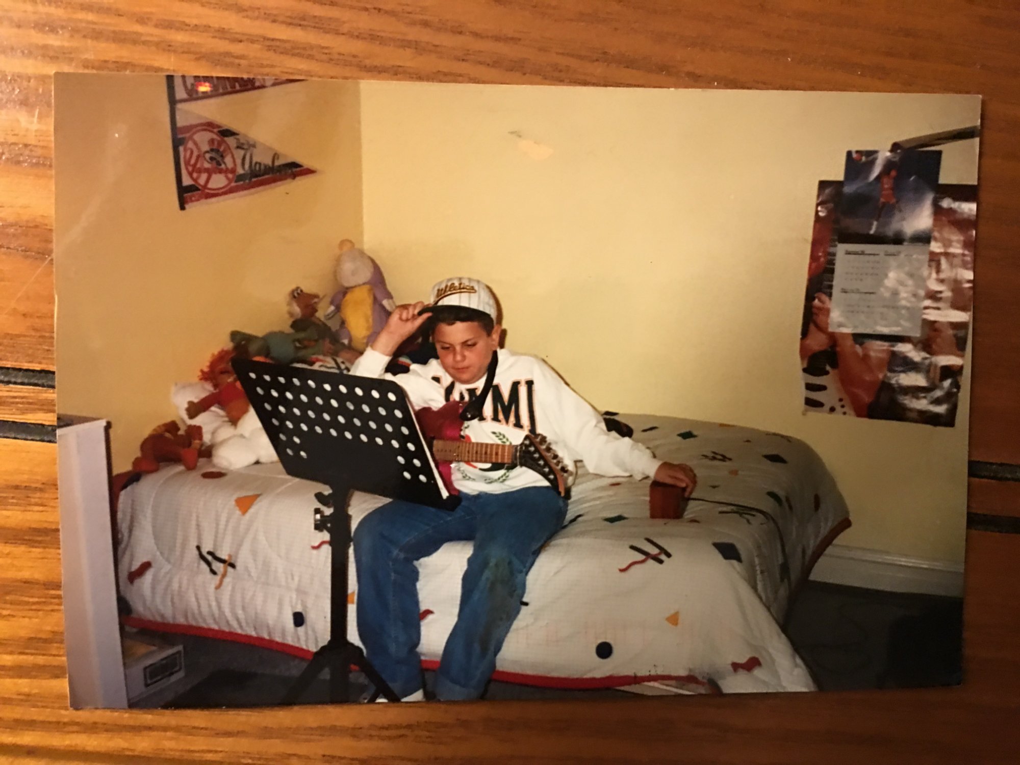 Young Matt Baron playing guitar on his bed